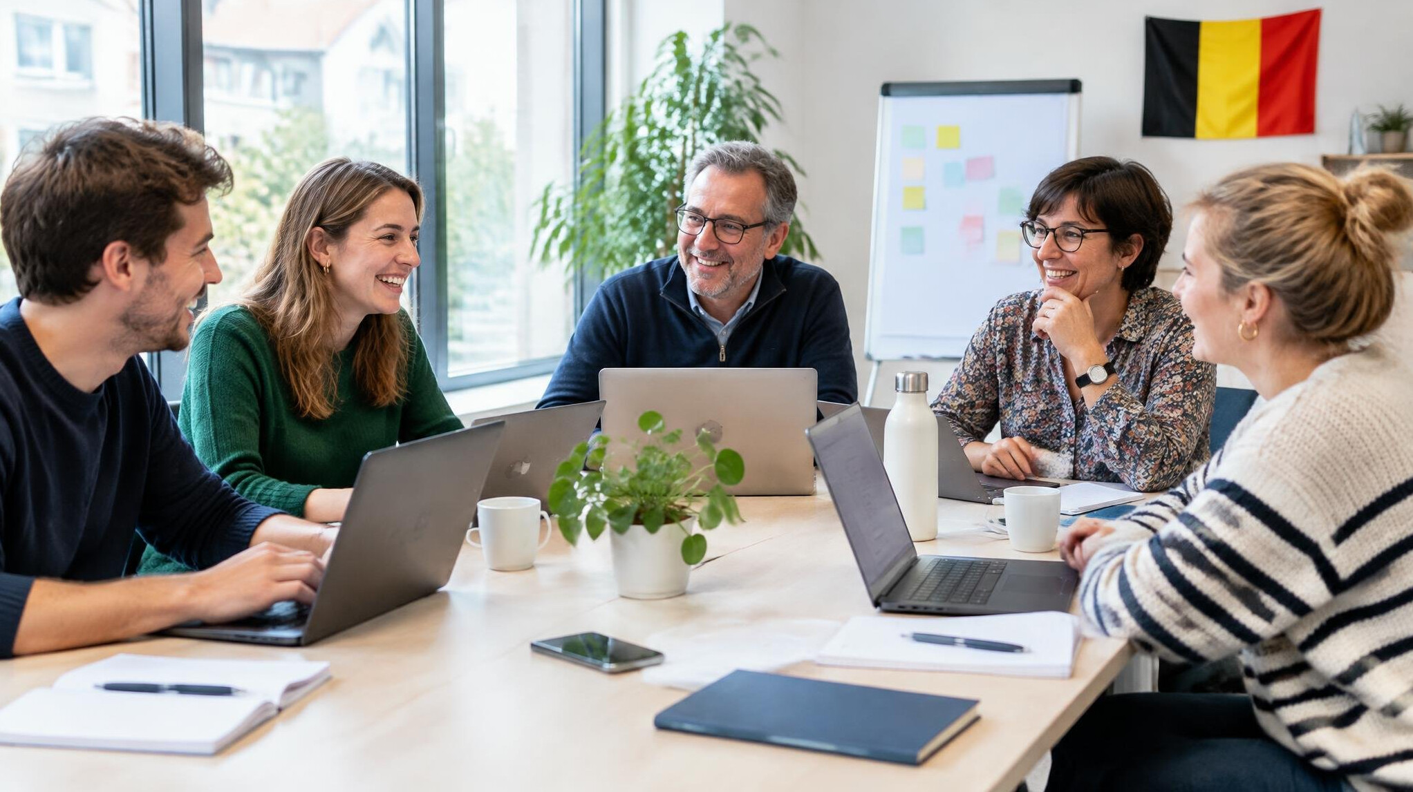 Group of people working together around a table with laptops