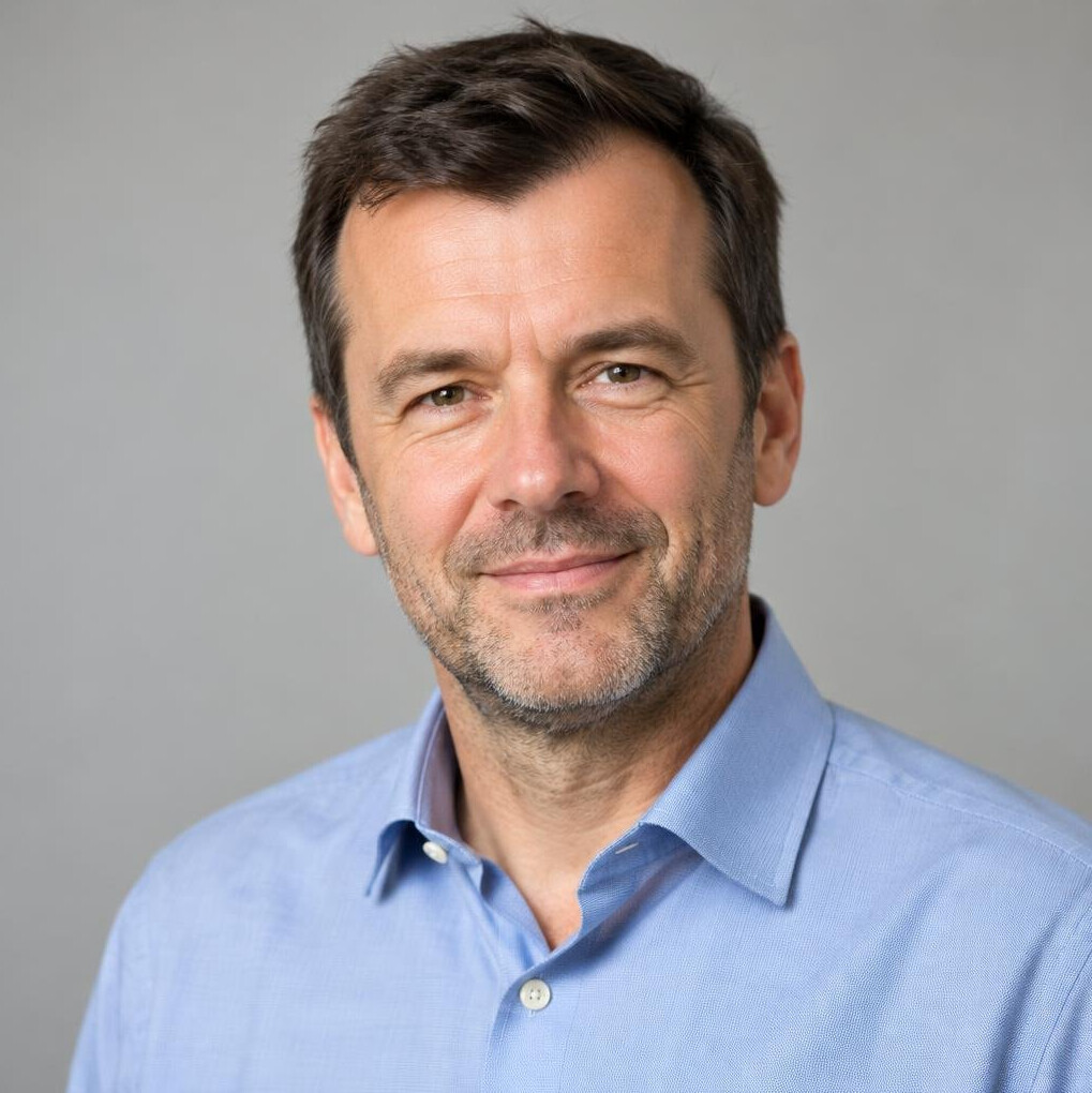 Man with short dark hair in a shirt smiling